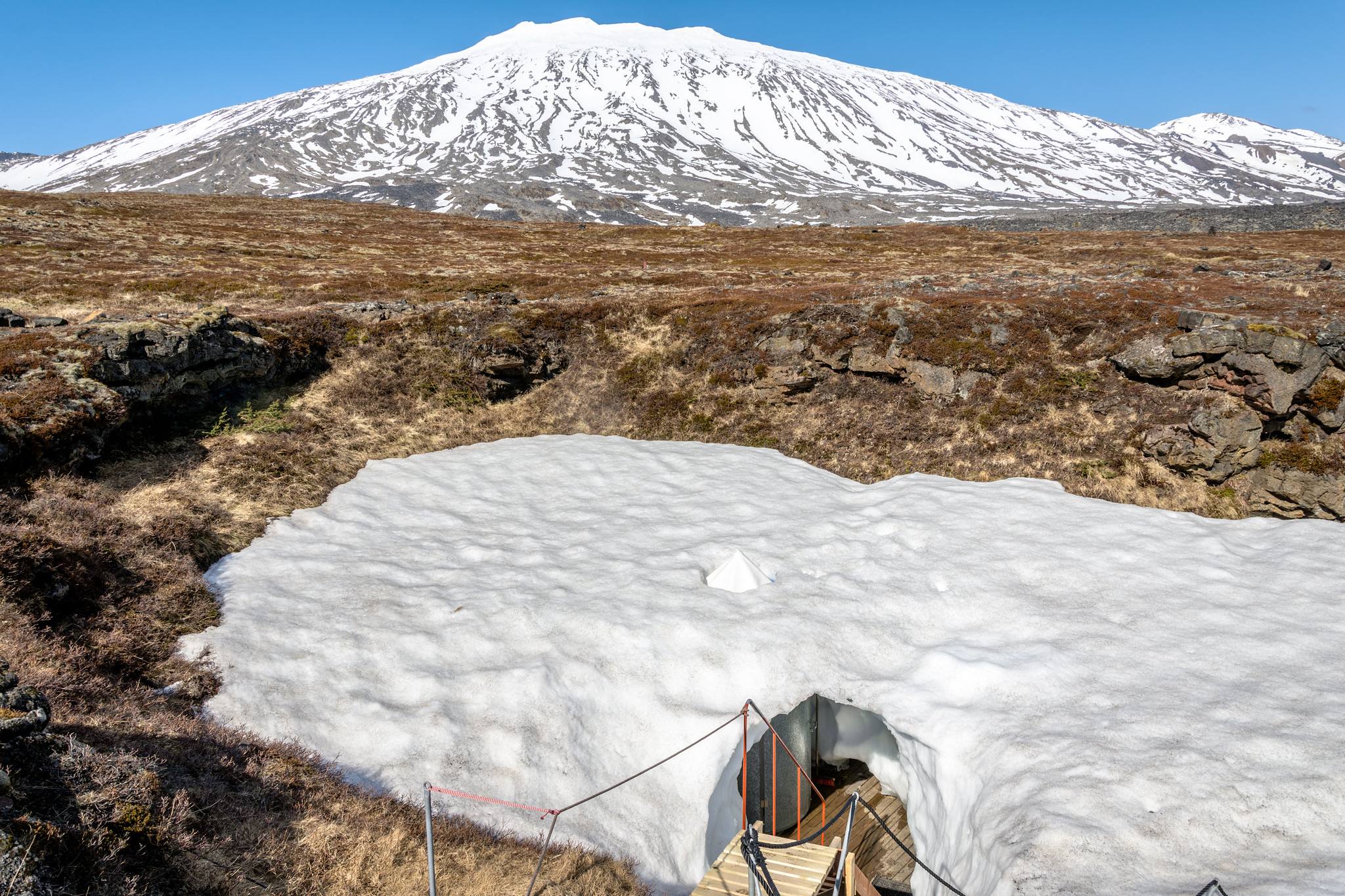 The entrance hut of Vatnshellir in a snow patch below the glacier